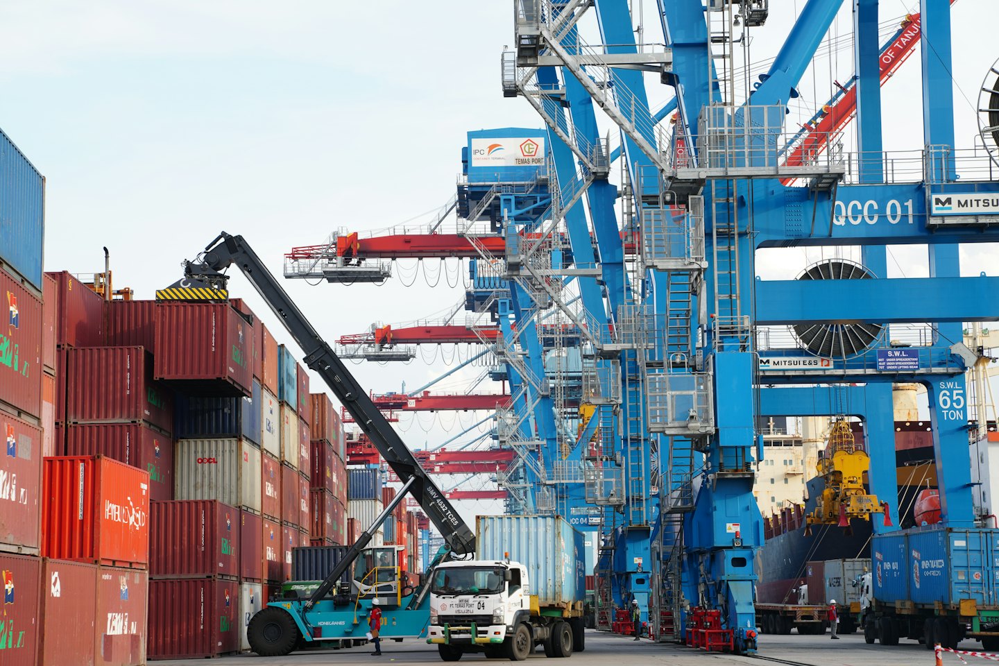 Container port with reach stacker moving a shipping container.
